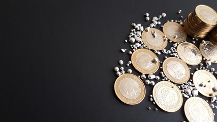 silver grains and coins on a black background