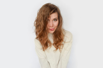 Obraz premium Playful girl shows tongue and smiles on white background.