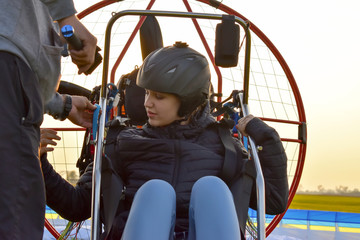 The instructor prepares the passenger for the flight. Preparing to fly on a motor paraglider. The...