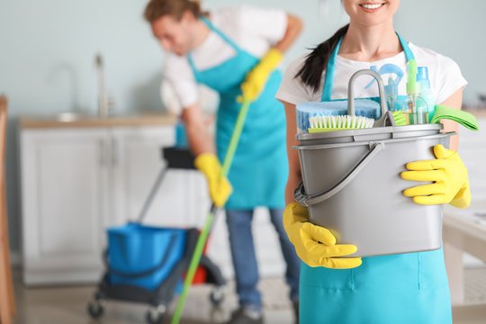 Female janitor with cleaning supplies in kitchen