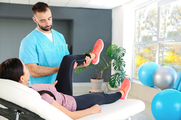 Physiotherapist working with female patient in rehabilitation center