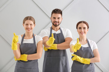 Team of janitors showing thumb-up gesture on grey background