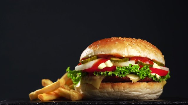 cheeseburger with french fries. Bun with beef meat, cheese, lettuce, tomato, onions, cucumbers, ketchup and mayonnaise