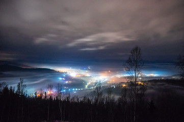 Night city in the fog in the mountains in autumn