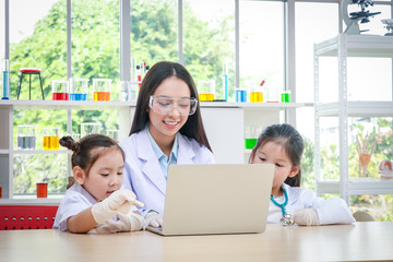 Beautiful researchers are teaching two girls who are interested in science in the laboratory.