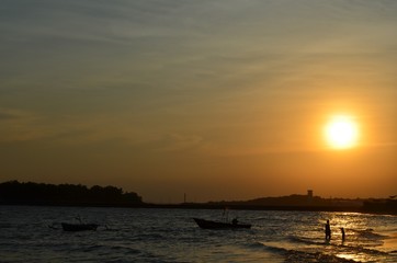 people silhouette play on the beach with the sunset as background and fisherman boat silhouette. in Borneo,Indonesia.