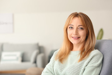 Beautiful mature woman sitting in armchair at home