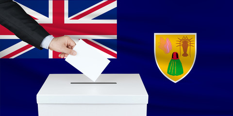 Election in Turks Caicos. The hand of man putting his vote in the ballot box. Waved Turks Caicos flag on background.