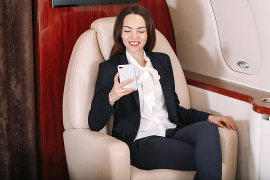 Businesswoman with mobile phone on board the modern private airplane