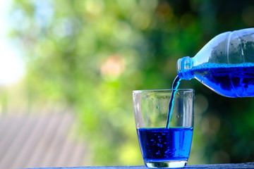 pouring fresh blue water into glass