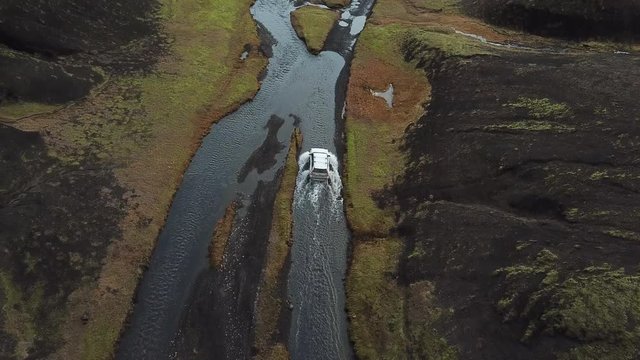 SUV Crossover Vehicle in Shallow River Moving Further on Muddy Road in Amazing Landscape of Iceland