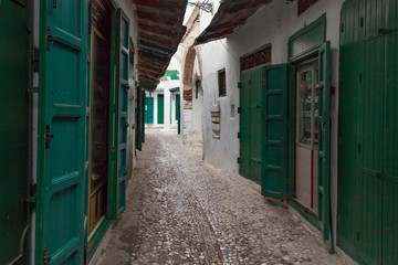 Fototapeta na wymiar Green wooden doors of the old stores in Tetouan Medina quarter in Northern Morocco. A medina is typically walled, with many narrow and maze-like streets.