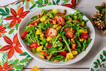 Green salad with arugula, strawberries, pineapple and pistachios. Christmas content.