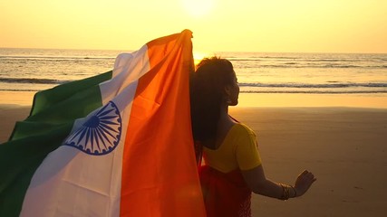 patriotism, independence day August 15 and holidays concept.happy smiling young woman with national indian flag on summer beach