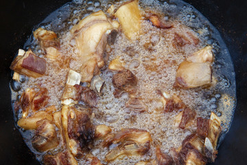 Pieces of lamb are fried in boiling oil on the fire. As a stage in the preparation of traditional pilaf.