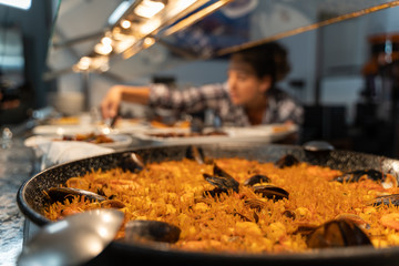 Fish-based dish at a self-service food counter with an unfocused girl in the background grabbing food