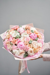 Pink peonies, Sarah Bernhardt and different flowers. European floral shop. Beautiful bouquet in womans hands. the work of the florist at a flower shop. Delivery fresh cut flower.