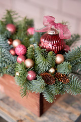 Closeup details of Small arrangement of fresh spruce in a rustic wooden box. Christmas mood. Bokeh of Garland, lamps lights on background.