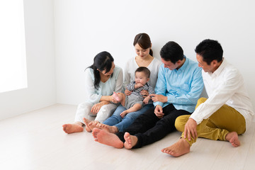 Fototapeta na wymiar 子供を抱っこして座っている3世代家族
