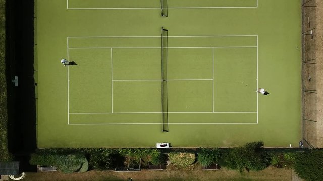 Showing two people playing tennis on Public tennis courts filmed from above with a drone in Thorpe bay Southend essex beach seafront in summer sunny day surrounded by residential houses and beach