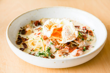 Pasta cream sauce with bacon and poached egg
