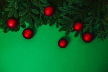 Fototapeta na wymiar Natural green fir branches flat lay with red christmas balls. Christmas card with copy space.