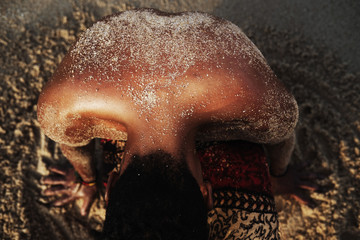 Sand on dark skin of african male back. Spa, aroma, perfume concept