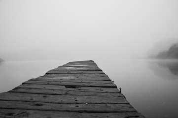Obraz na płótnie Canvas Wooden footbridge on lake with thick mist foggy air over water. Early chilly morning in late autumn. Empty place(copyspace) for text, quote or sayings. Concepts: peaceful, mindfullness, secret, nature