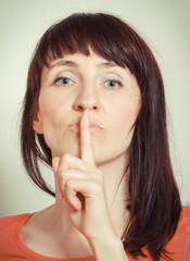 Naklejka premium Woman holding finger to lips and showing silence sign