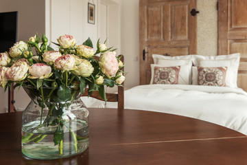 Fresh roses flowers on wooden table in modern bedroom
