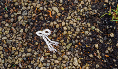 A piece of white braided plastic cordage isolated on a dark bitumen surface image with copy space