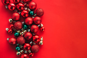 Red background with christmas balls on one side, space for text, flat lay.