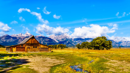 An abandoned Barn at Mormon Row with in the background cloud covered Peaks of the Grand Tetons In Grand Tetons National Park near Jackson Hole, Wyoming, United States