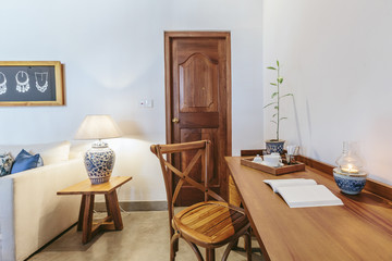 Modern hotel room interior with working space, wooden desk, chair, book and lamp