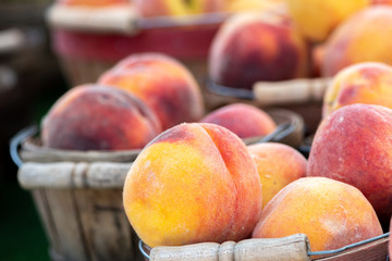 Close up image of wooden baskets of peaches at a farmers market