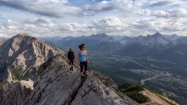 Cinemagraph of an Adventurous Girl is hiking up a rocky mountain during a cloudy and rainy day. Taken from Mt Lady MacDonald, Canmore, Alberta, Canada. Still Image Animation Continuous Loop