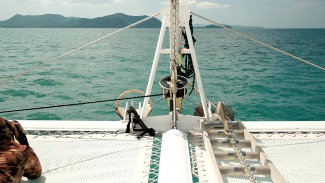Front view of yacht sail through the ocean with day light and the photographer lie on bow and take some picture.