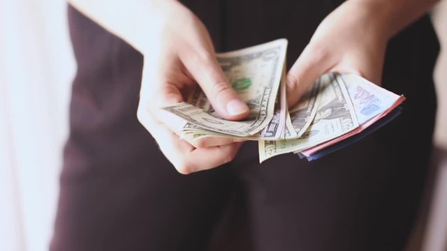 Woman traveler's hands recounts her cash money in different currencies
