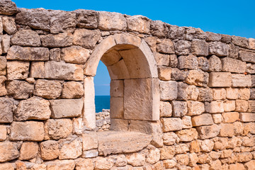 antique stone wall with arched opening and sea view