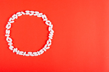 White medical pills composition on red background.