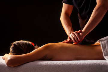 Obraz premium Masseur hands doing back massage to client in spa center in dark room