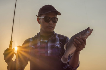 A fisherman enjoying a holiday with a big fishing reward at sunset.