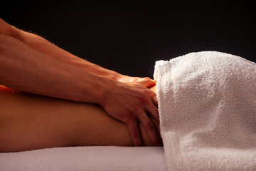 Masseur hands doing back massage to client in spa center in dark room