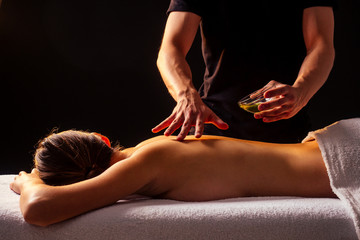 close-up masseur hands doing back massage to female client in spa center