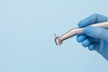 Dentist's hand in glove with dental handpiece.