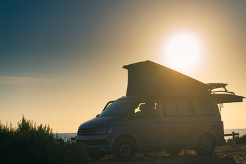 Fototapeta na wymiar Camper van with tent on roof at sunset