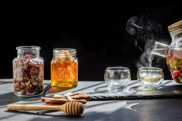 Still life book and a cup of tea on a wooden table,process brewing tea,Cup of freshly brewed fruit and herbal tea, darker background. .Hot water is poured from the kettle into a cup with tea.