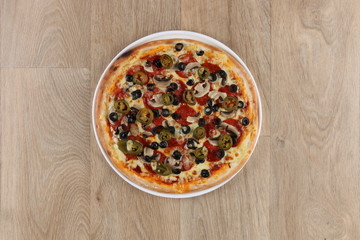 Pepperoni pizza with vegetables on a wooden background - salami