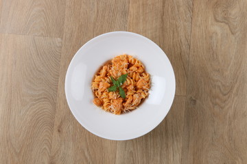 Fusilli with Shrimp pasta with basil leaves and Parmesan cheese in a white plate on a wooden background
