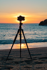 Camera standing on a tripod on the beach against the background of dawn